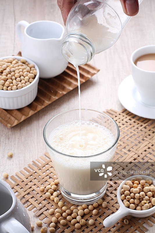 在印度尼西亚西爪哇省勿加泗市，女人在桌子上的咖啡杯里倒牛奶的裁剪手部照片图片素材