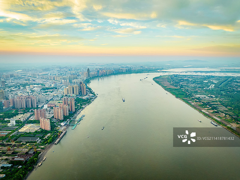 日出时分金黄色温暖的阳光洒向长江两岸，蜿蜒的长江向天边延伸拐弯，江面船只游弋图片素材