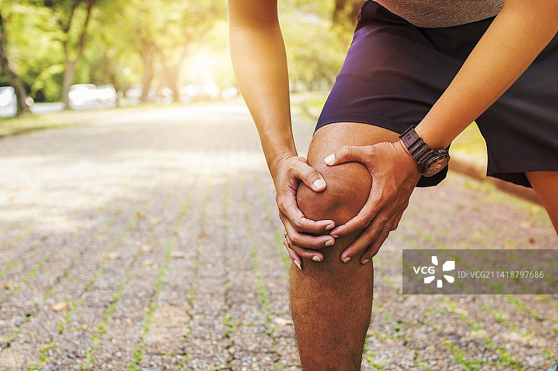 站在人行道上触摸膝盖的女子腰部特写图片素材