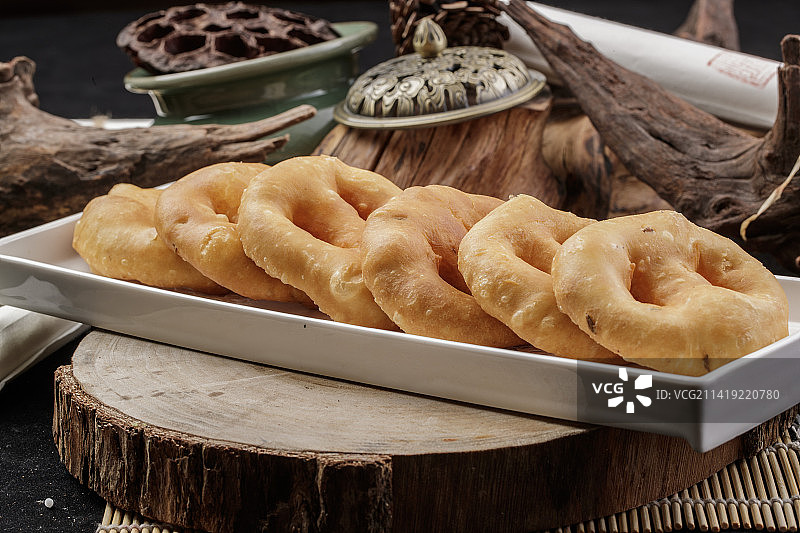 长方形瓷盘装的香炸小油饼摆放在樟木砧板上图片素材