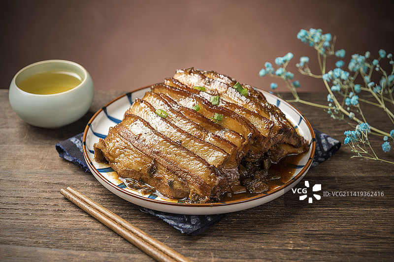 一盘梅菜扣肉摆放在木桌面上特写图片素材