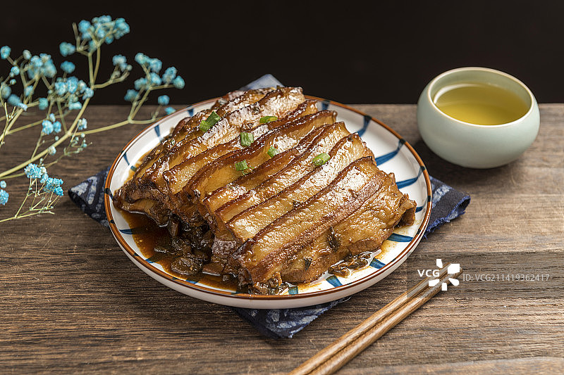 一盘梅菜扣肉摆放在木桌面上特写图片素材