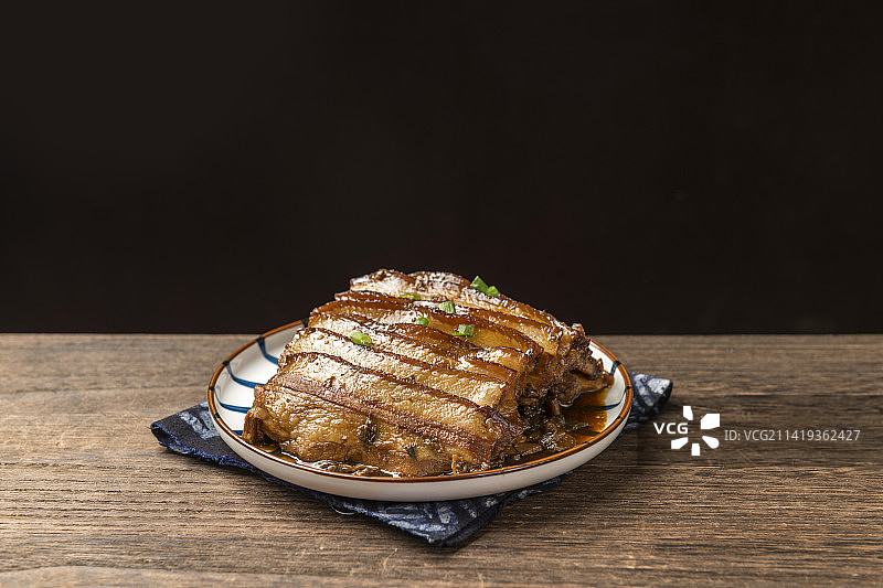 一盘梅菜扣肉摆放在木桌面上特写图片素材