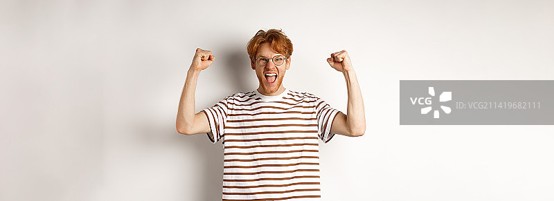 快乐的红发男子举起双手，像个胜利者图片素材