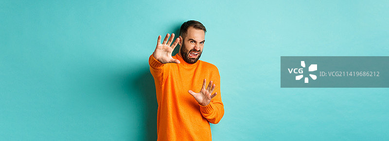 感到厌恶的男人畏缩着，伸出手保护，乞求着图片素材