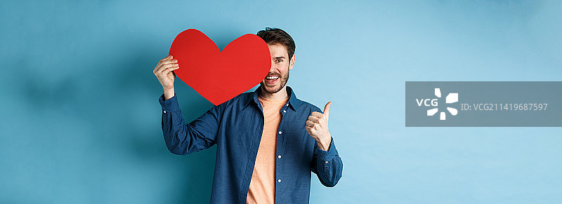 快乐的男人展示情人节爱心并竖起大拇指图片素材