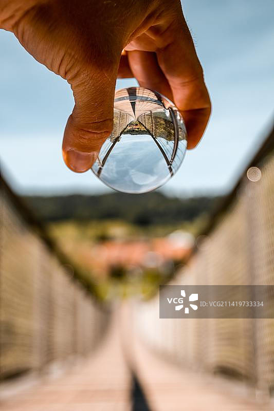 手持水晶球特写，反射桥梁天空图片素材