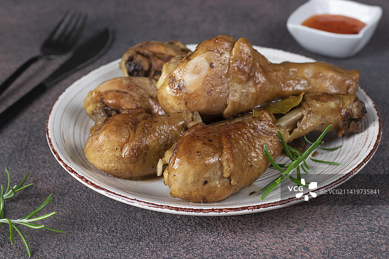 烤鸡腿，以酱油、蜂蜜和迷迭香调味，置于棕色背景的盘中（罗马尼亚）图片素材