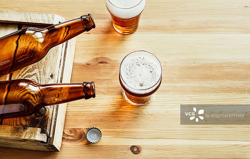 罗马尼亚：木质背景上的两只空啤酒瓶和两杯啤酒图片素材