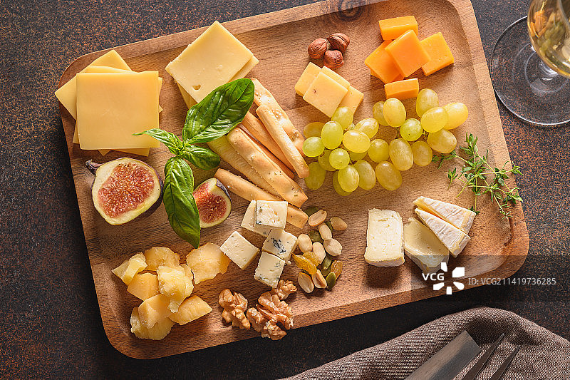 棕色背景上的奶酪拼盘，搭配葡萄、坚果、无花果，顶视图，留有复制空间，罗马尼亚图片素材