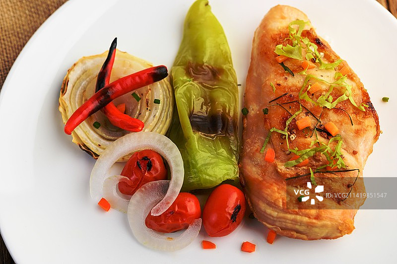 白盘烤鸡配番茄、沙拉、洋葱、辣椒和酱汁图片素材