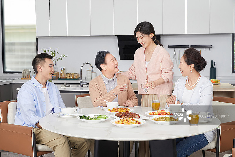 在一起吃饭的一家四口给父亲倒酒图片素材