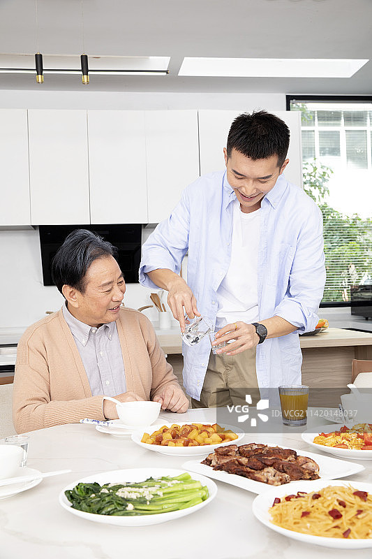 站起来给父亲敬酒的年轻男人图片素材