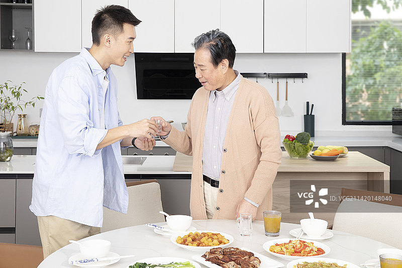 站起来给父亲敬酒的年轻男人图片素材