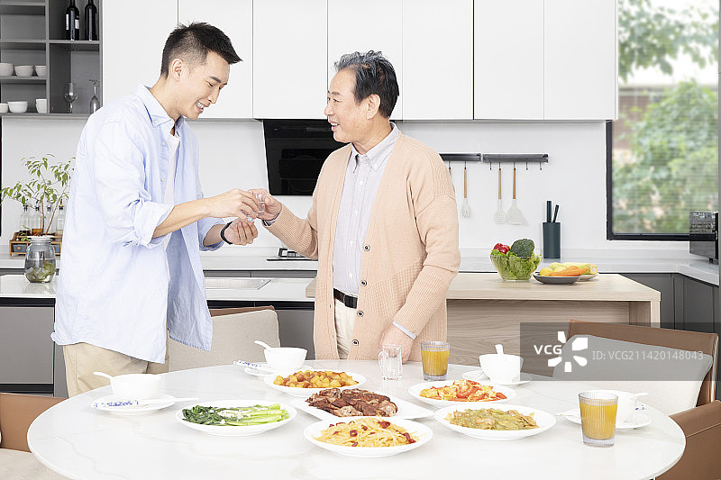 站起来给父亲敬酒的年轻男人图片素材