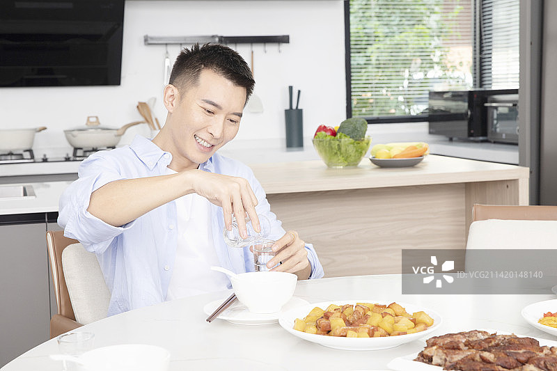 坐在餐桌旁喝酒的年轻男人图片素材