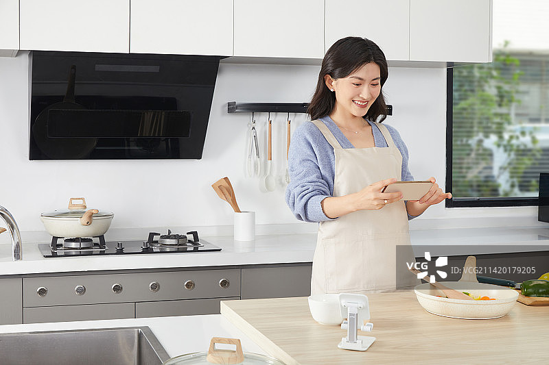 手拿锅铲的年轻女人在厨房忙碌图片素材