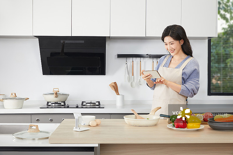 手拿锅铲的年轻女人在厨房忙碌图片素材