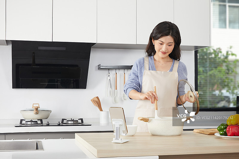 在厨房使用汤锅的年轻女人图片素材