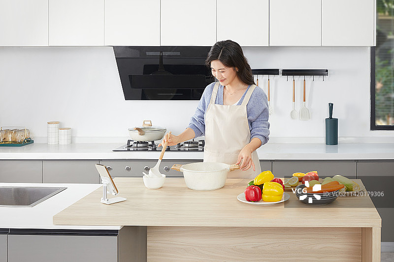 在厨房使用汤锅的年轻女人图片素材