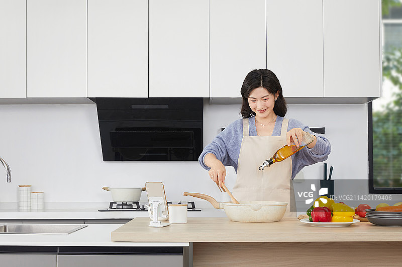 手拿锅铲的年轻女人在厨房忙碌图片素材
