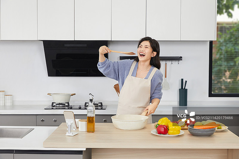 手拿锅铲的年轻女人在厨房忙碌图片素材
