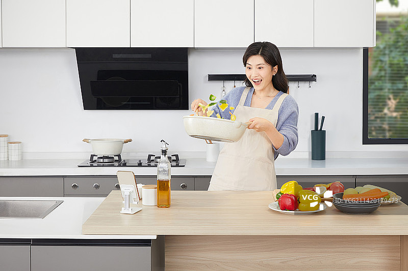 手拿锅铲的年轻女人在厨房忙碌图片素材