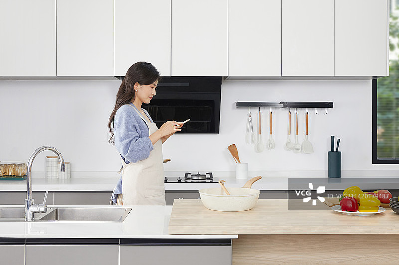 手拿锅铲的年轻女人在厨房忙碌图片素材