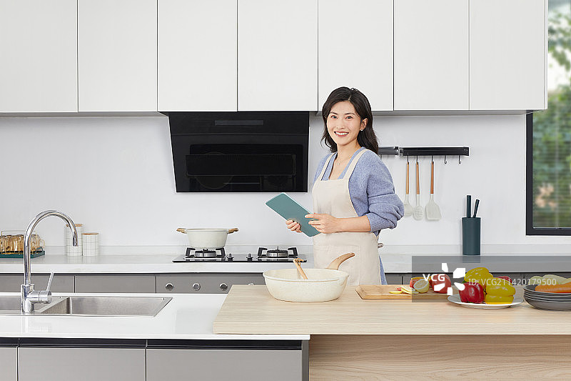 手拿锅铲的年轻女人在厨房忙碌图片素材