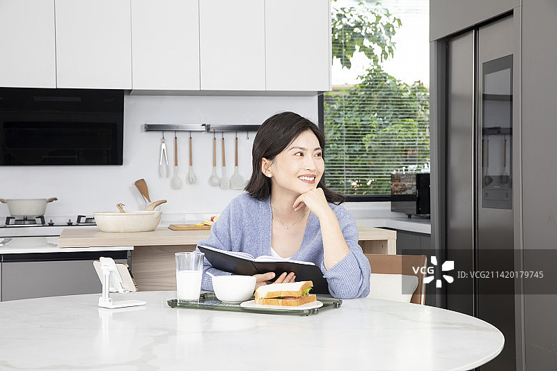 居家办公翻阅笔记本的年轻女性图片素材