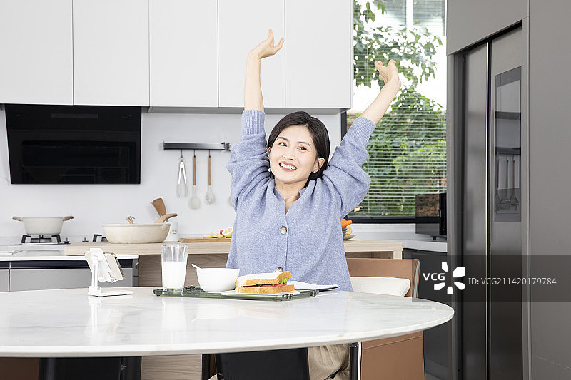 伸懒腰吃个早餐的年轻女性图片素材