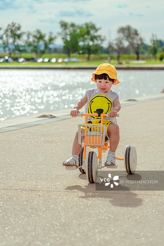 植物园湖畔骑三轮童车的小男孩图片素材