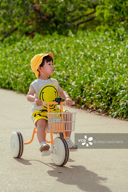 花园小道骑三轮童车的小男孩图片素材