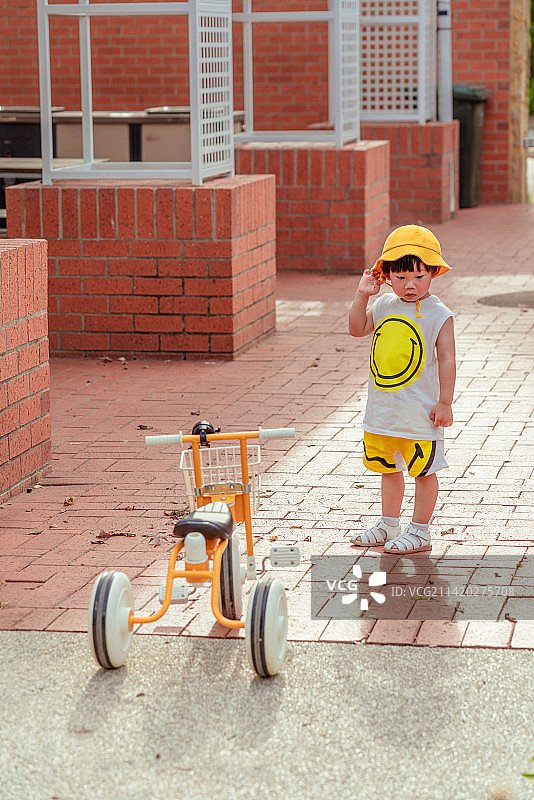 风景区红砖建筑处骑三轮童车男孩图片素材
