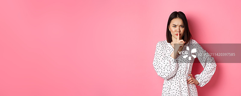 愤怒的亚洲女性模特在做嘘声手势，皱着眉头并发出嘘声，展示禁忌图片素材