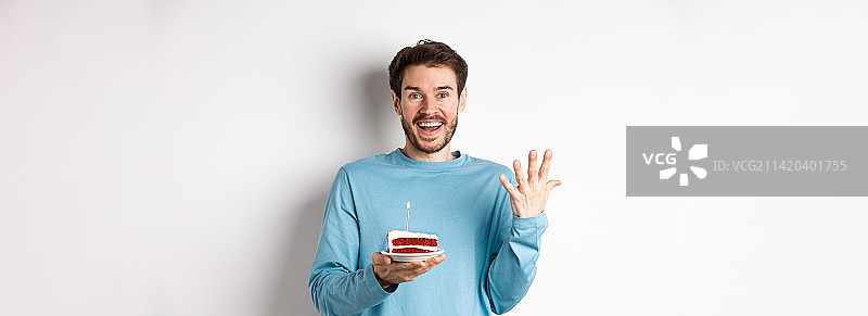 兴奋的男人收到生日惊喜，拿着生日蛋糕微笑图片素材