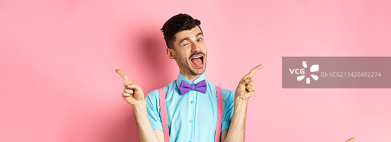 快乐的年轻人微笑和眨眼，展示两面，指点图片素材