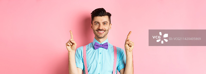 对着镜头微笑，向上指的快乐英俊男子图片素材