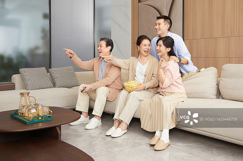 陪伴父母坐在客厅里看电视青年男女图片素材