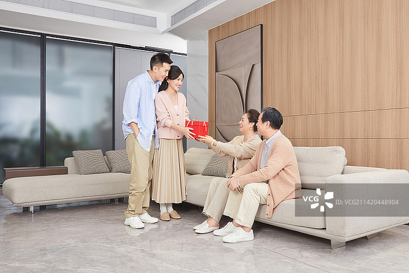 陪伴父母坐在客厅里的青年男女图片素材