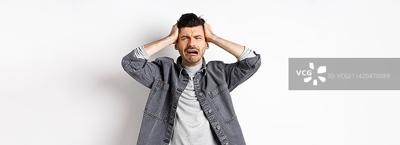 沮丧的家伙哭泣和恐慌，双手抱头图片素材