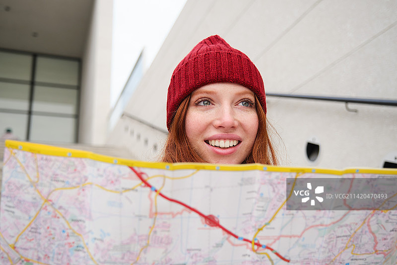 拿着城市地图坐在楼梯上的漂亮女游客，规划她的旅程图片素材