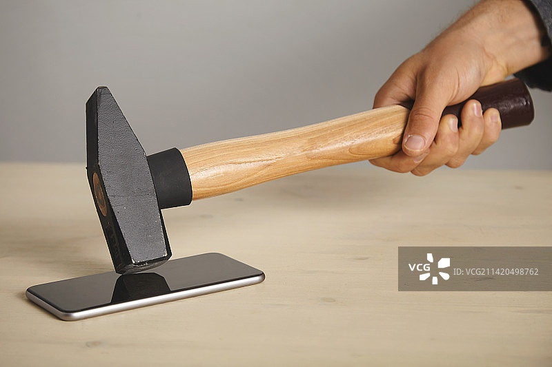 手部特写拿着锤子在桌子上，印度尼西亚图片素材