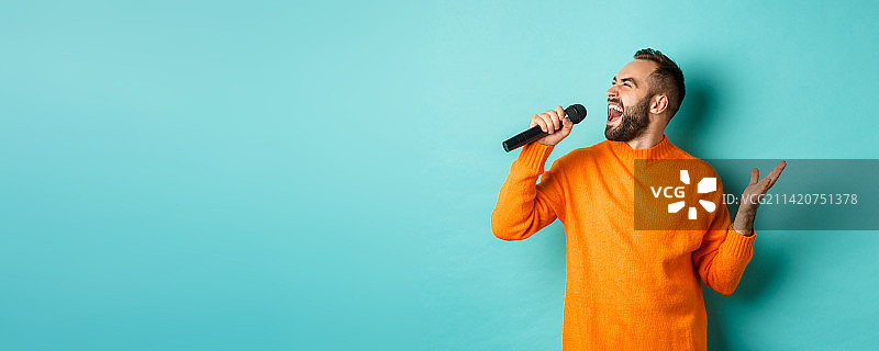 英俊男子唱歌，站在麦克风前图片素材
