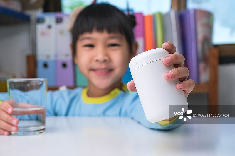 可爱的泰国小女孩正在吃鱼油或维生素药丸图片素材