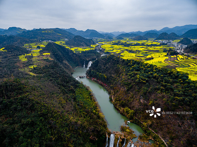 航拍春季盛开的云南曲靖罗平九龙瀑布群与油菜花海图片素材