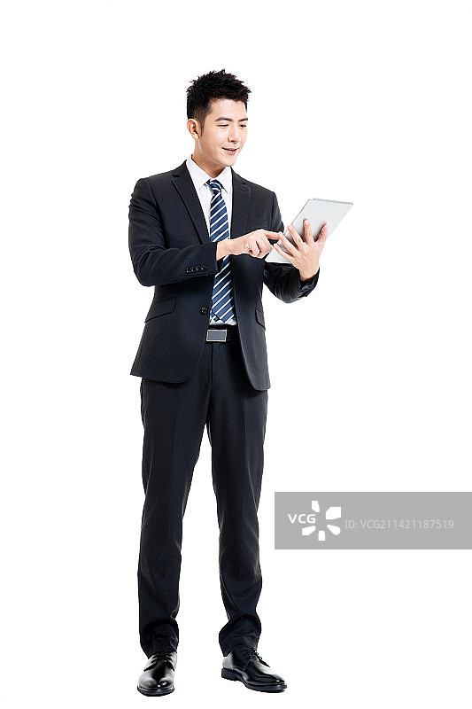 身着深色西装套装手拿平板电脑的年轻男士图片素材