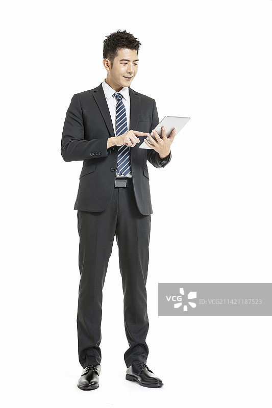 身着深色西装套装手拿平板电脑的年轻男士图片素材