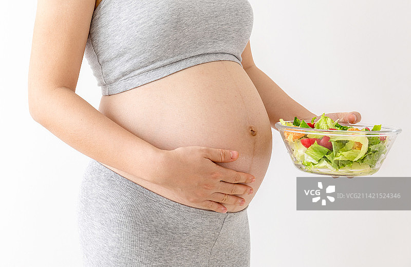 一位年轻孕妇手里拿着一碗沙拉图片素材