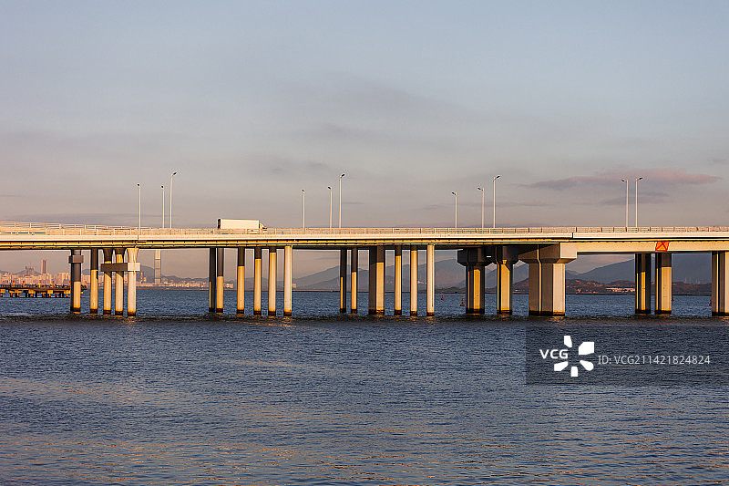 夕阳金色阳光下行驶在深圳湾公路大桥上的深港车辆图片素材
